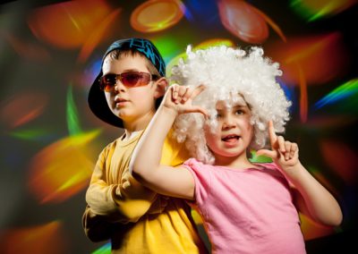 A boy and girl posing with a wig and glasses at a kids' disco party